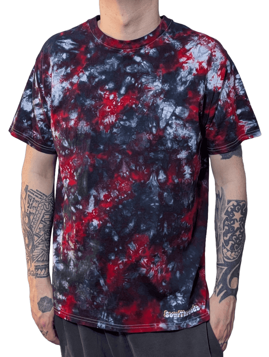 Person wearing a tie-dye t-shirt with red, black, and white patterns on a plain background