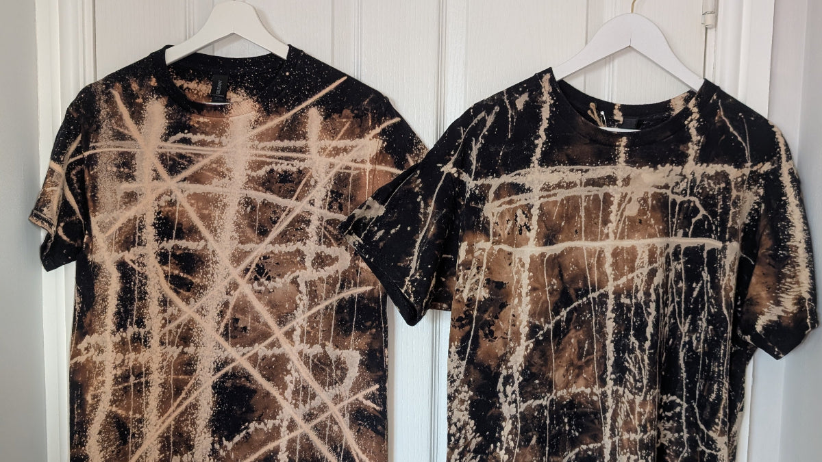 Two bleached  tie-dye t-shirts hanging on a white door.